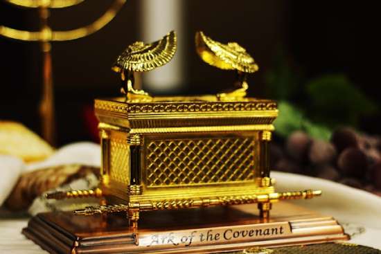 A small model of the Ark of the Covenant, covered in gold, with two angels on the top, wings pointing to the center.