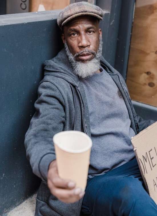 A homeless man holding up a sign for help