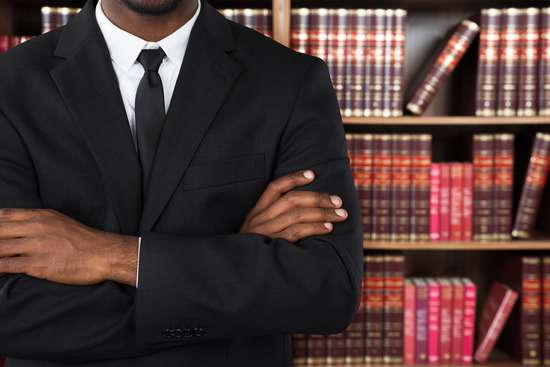 A lawyer in a suit, standing by a full bookcase