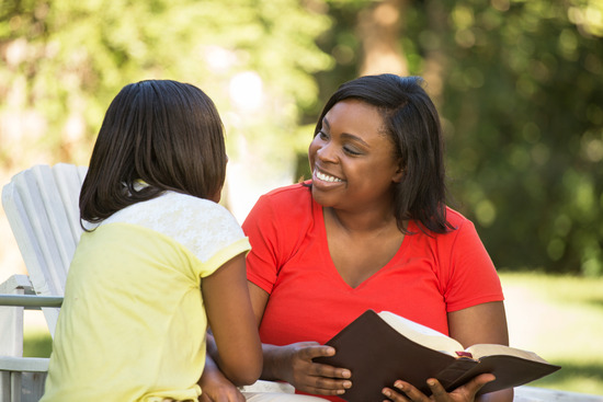 A mother and daughter sit outside as they study the Bible together.