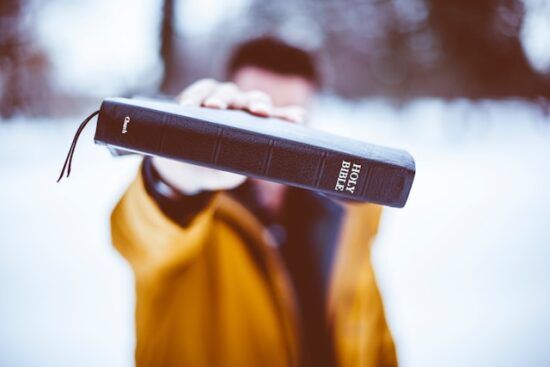 Man extending Bible to anyone who is facing moral issues to find guidance in it on how to respond as God would have them