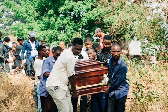 A group of people carry a wooden coffin to burial grounds.