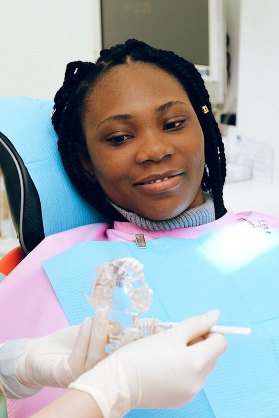  A patient watches as her dentist demonstrates the proper way to brush teeth.