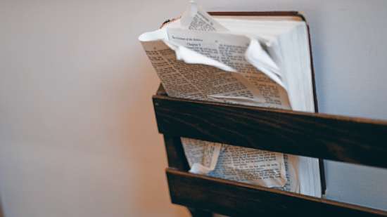 A coverless Bible stuffed into a rack, the front pages wrinkled and bent