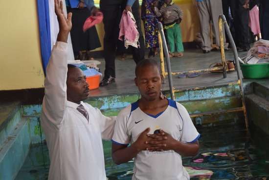 A pastor baptizes a young man in a pool