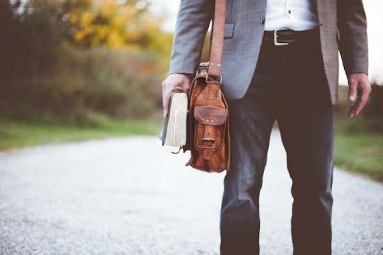 A man stands in the road with a Bible in his hands, as if he is walking to church to praise with other believers.