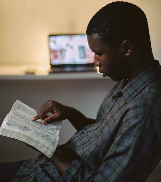 A man reads his Bible, his finger pointing to a specific verse to show his engagement. Perhaps he is reading about conflict resolution principles.