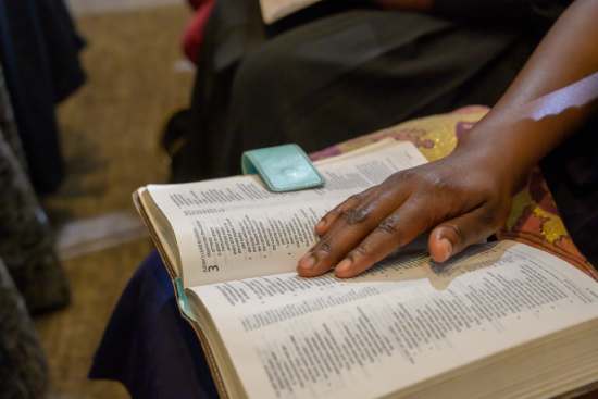  woman studies the Bible intently. She has her finger following a specific line of text.