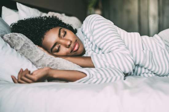A young woman sleeps peacefully in her bed, practicing the importance of rest as part of God's instruction for healthy living.