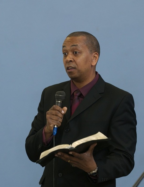 An Adventist pastor holds an open Bible as he preaches to his congregation.