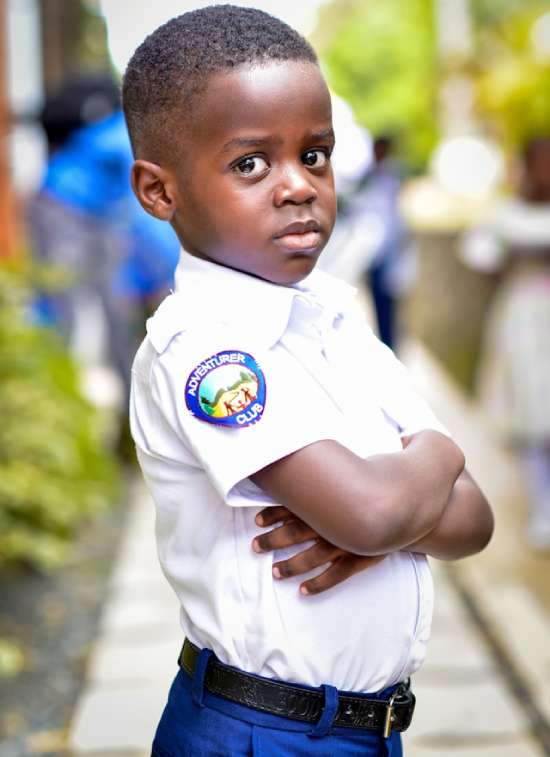 A young boy standing and wearing an Adventurer uniform