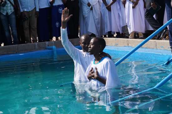 A pastor baptizing a young man who has chosen to follow Jesus