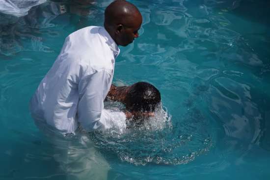 A pastor baptizes a person by quickly submerging them in water and bringing them back up, symbolizing how someone chooses to bury their old, sinful life and accept the new, righteous life Jesus offers.