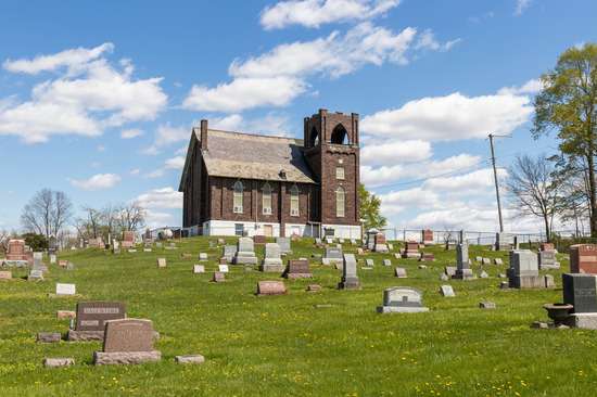 A stone church with a graveyard outside