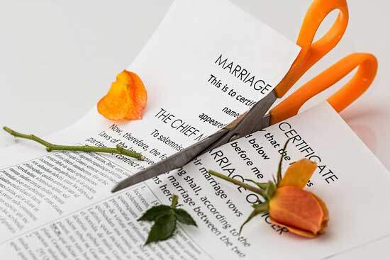 A marriage certificate being cut in half with scissors after a divorce