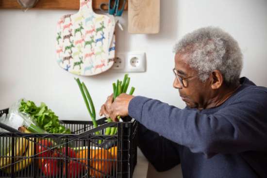 An elderly man admires a basketful of vegetables, illustrating how following the Adventist diet can lead to a long and healthful life.
