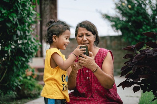 A girl showing her grandmother something on her phone