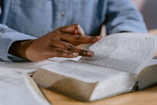 A young man's hands flipping through the pages of the Bible.