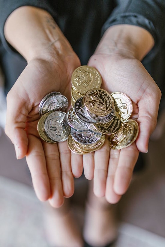 A pair of hands hold a pile of coins.