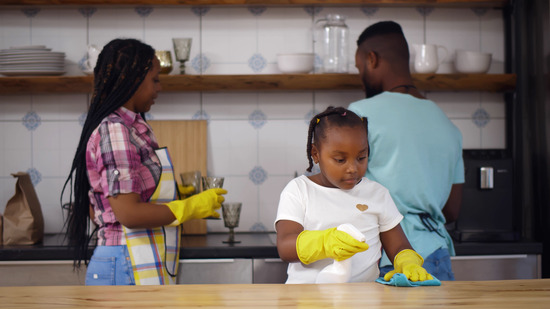 A mother, father, and daughter cleaning together in the kitchen