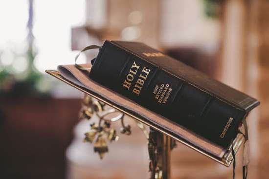 A Bible rests on a podium at the front of a church, emphasizing it as the standard of all spiritual truth