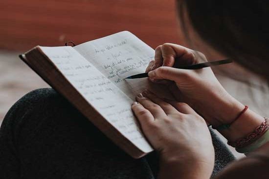 A woman writing daily journal as a way of reducing anxious thoughts 