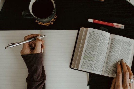 An individual studying Scripture with a notebook and pen