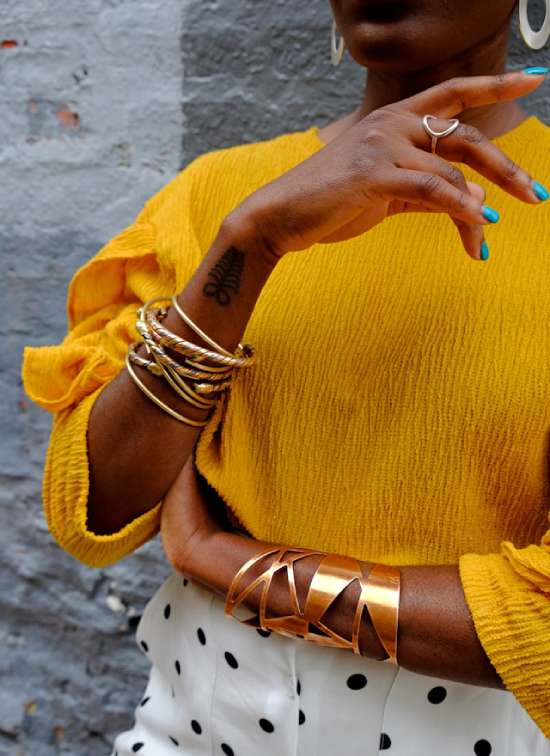 A woman wearing gold jewelry, fancy clothes, and showing a tattoo, symbols of the people of the last days