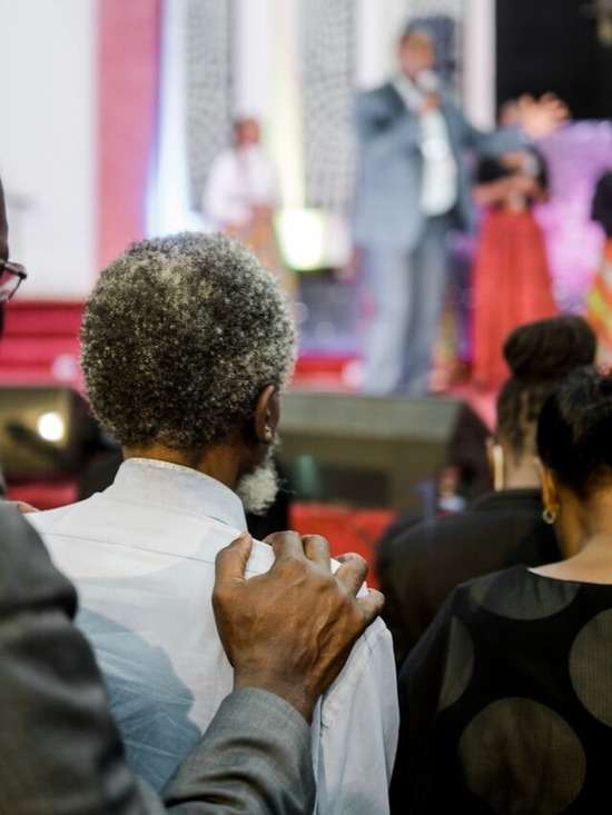A man listens to his Pastor preach in church, while being comforted.