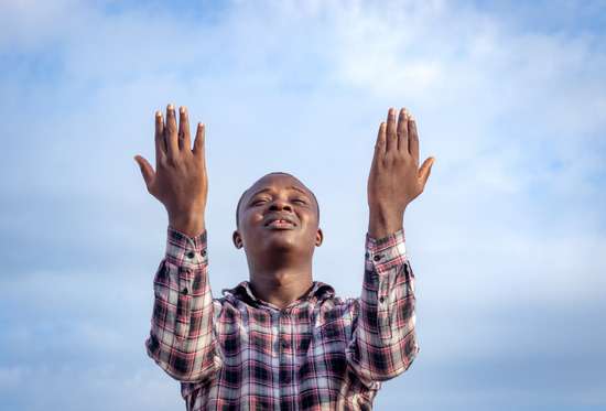 Man with both hands raised to heaven as he prays humbly to God for His wisdom