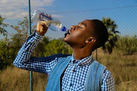A man drinking water in plastic bottle.
