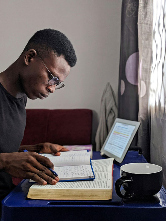 A man studying Bible verses with a notebook and tablet, illustrating reading the Bible in the version that suits you.