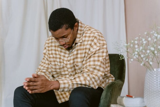 A man sits with his hands folded and prays. 