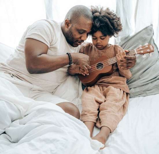 Dad teaching his son how to play the ukulele.