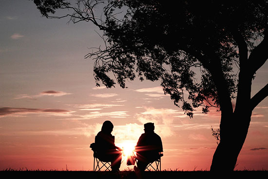 Two Adventists sit together outside to watch the sun set on Sabbath