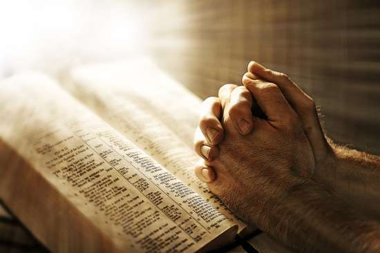 Two Hands over the Bible in Prayer