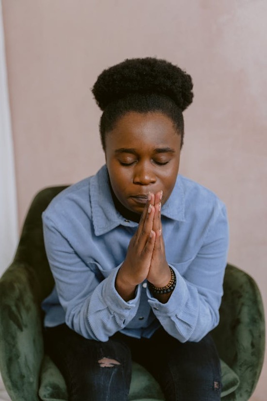 A young woman prays with folded hands.