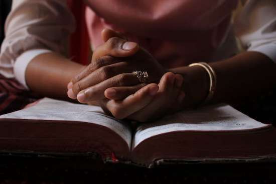 A woman praying over an open Bible that her life be governed by God, under the conviction of the Holy Spirit.