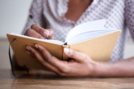 A close up of a woman’s hands writing in a journal, highlighting how journaling can enrich our spiritual lives.